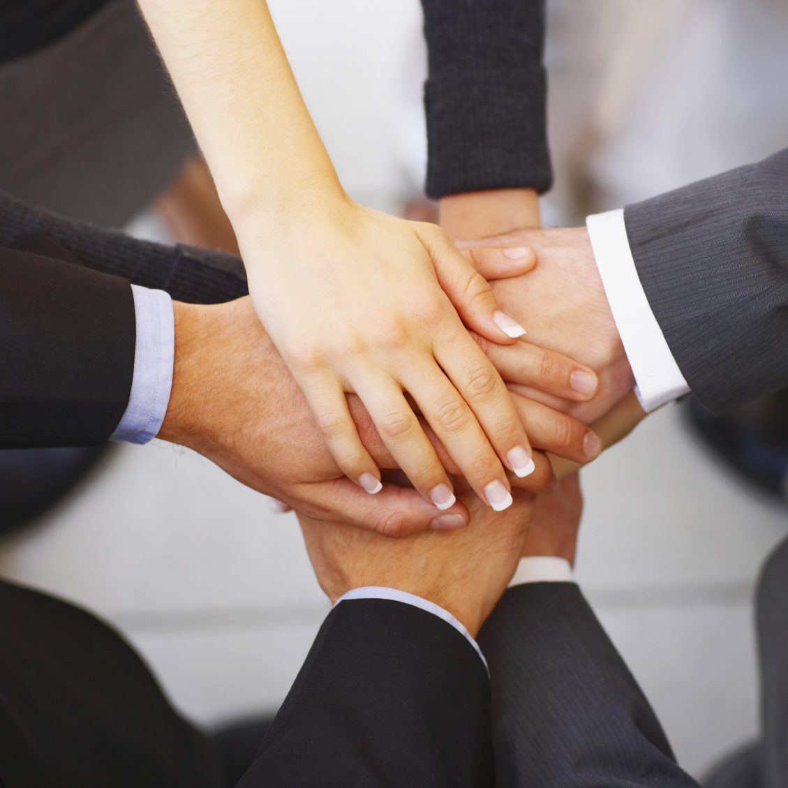 A group of hands stacked together in a display of teamwork and unity.